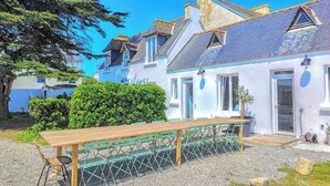 A coastal building with a wooden bench, a gravel path, and a clear blue sky.