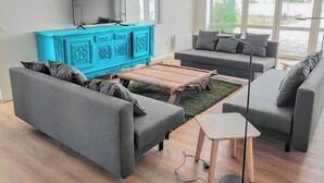 A modern living room with grey sofas, a wooden coffee table, and a blue cabinet.