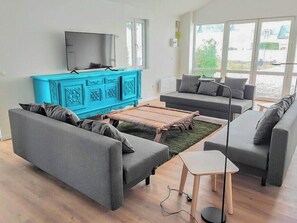 Un salon moderne avec des canapés gris, une table basse en bois et un meuble bleu.