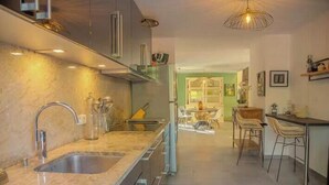 Une cuisine moderne dotée d’un îlot central, d’appareils électroménagers en acier inoxydable et d’un coin repas avec des chaises.