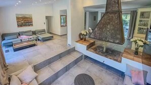Un salon moderne comprenant un canapé, une table basse, une cheminée et un escalier menant à un autre niveau.