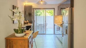 Une cuisine moderne avec un coin repas, une grande porte-fenêtre coulissante donnant sur un espace extérieur et un luminaire au plafond.