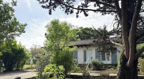 A traditional house with a tiled roof, surrounded by greenery and a stone wall. - La Maison des Acacias (MARTEL)