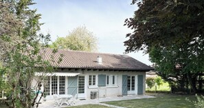 Ein Haus mit Ziegeldach, einer Terrasse mit Tisch und Stühlen und einem Rasen.