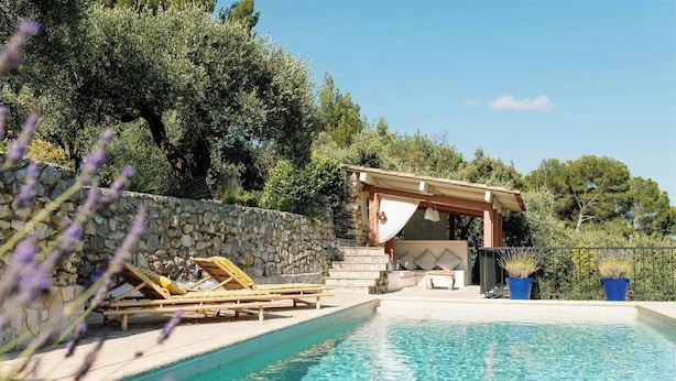 Ein Poolbereich mit Liegestühlen, einer Steinmauer und einer Pergola.