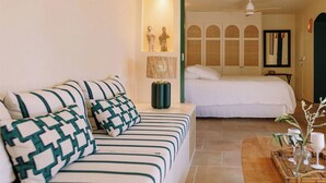 Ein Hotelzimmer mit einem Bett, einem Sofa, einem kleinen Tisch mit einer Vase und einem an der Wand befestigten Regal mit Dekoration.