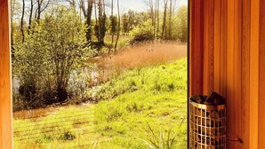 Een kamer met een groot raam, met uitzicht op een grasveld en bomen.