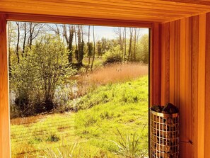 Ein Zimmer mit großem Fenster und Blick auf ein Wiesfeld und Bäume.