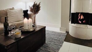 Un salon moderne avec une cheminée, un canapé, une table basse avec des bougies et une lampe.