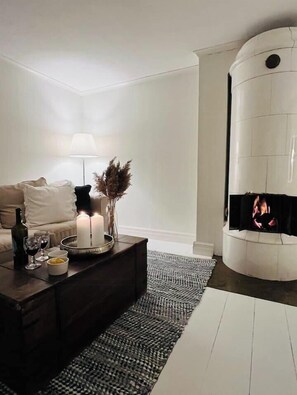 Ett modernt vardagsrum med en öppen spis, en soffa, ett soffbord med ljus och en lampa.