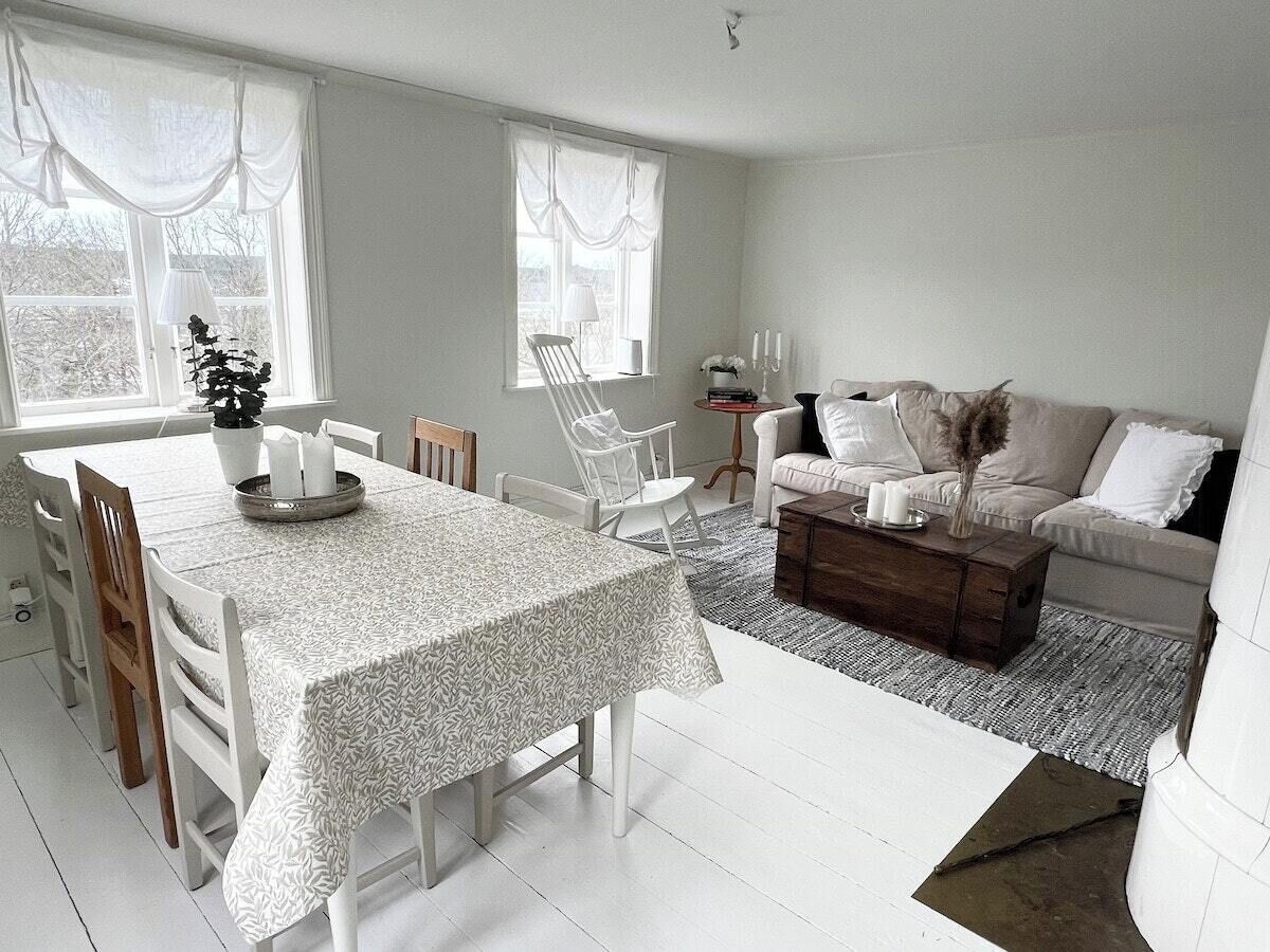 A living room with a dining table, white chairs, a sofa, and a coffee table.
