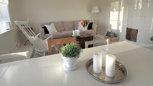 Un salon avec un canapé, une table à manger, une plante en pot et des bougies.