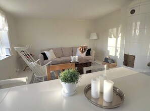 Ett vardagsrum med en soffa, ett matbord, en krukväxt och ljus.