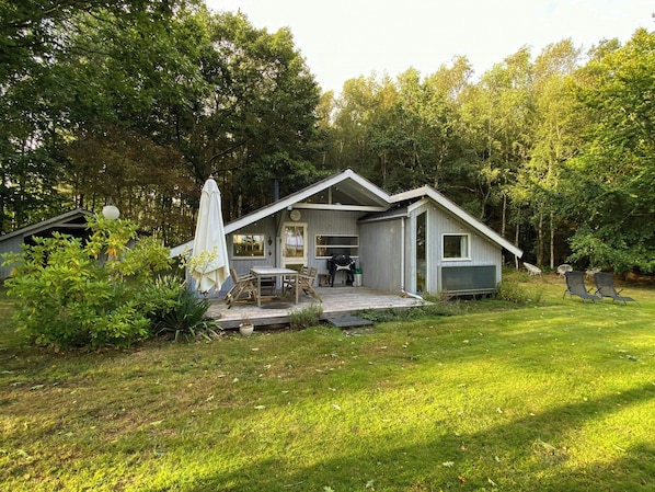 Une cabane avec une terrasse, un espace salon extérieur et un garage.
