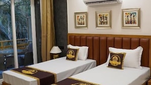 A hotel room with two beds, a ceiling fan, an air conditioning unit, and a window with a view.