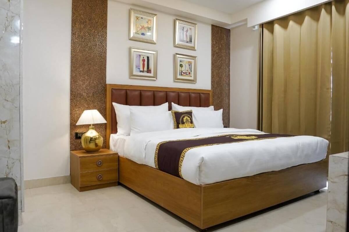 A hotel room with a large bed, a nightstand with a lamp, and a wall with framed pictures.