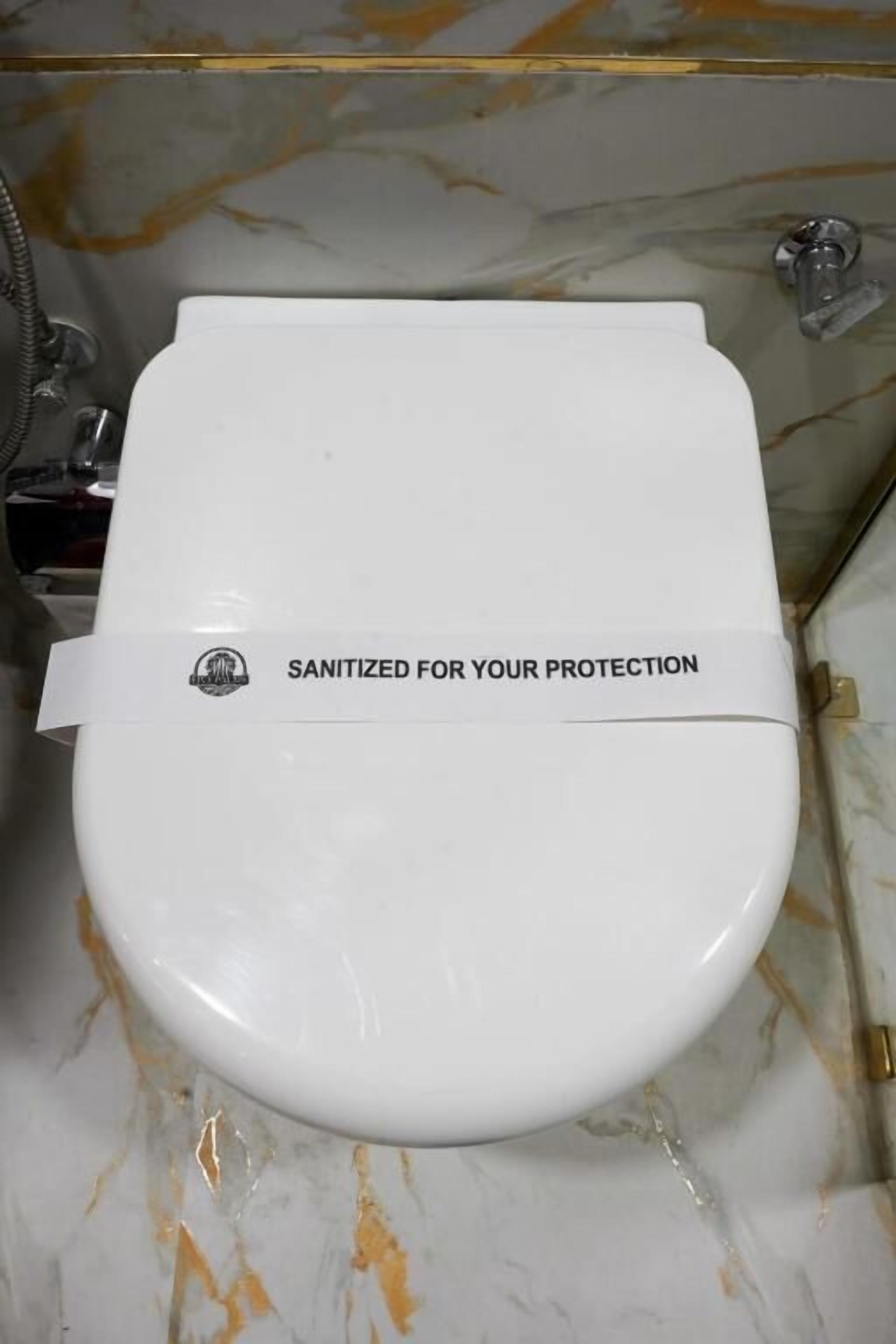 A white toilet with a label that reads 'SANITIZED FOR YOUR PROTECTION'.