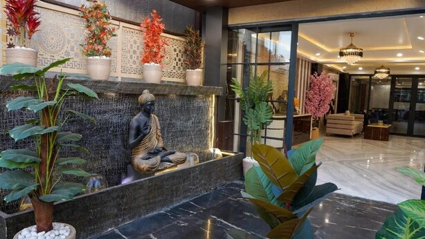 A modern lobby with a stone fountain, indoor plants, and a Buddha statue. - Five Palms Hotels (Gurugram)