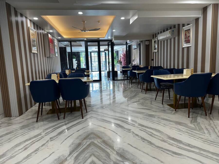 A hotel lobby with a marble floor, blue chairs, and a ceiling fan.
