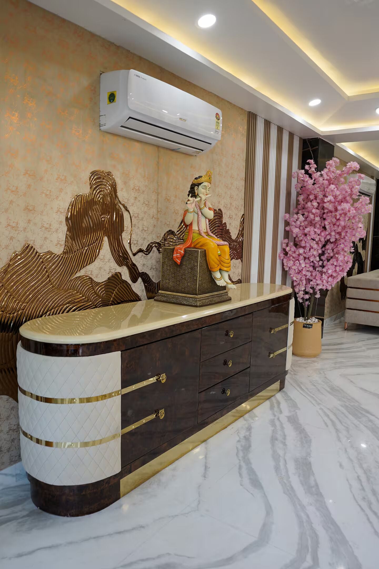 A modern interior with a marble floor, a decorative statue, a wall-mounted air conditioner, and a potted flowering plant.
