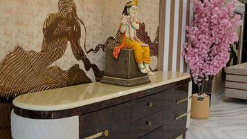 A modern interior with a marble floor, a decorative statue, a wall-mounted air conditioner, and a potted flowering plant.