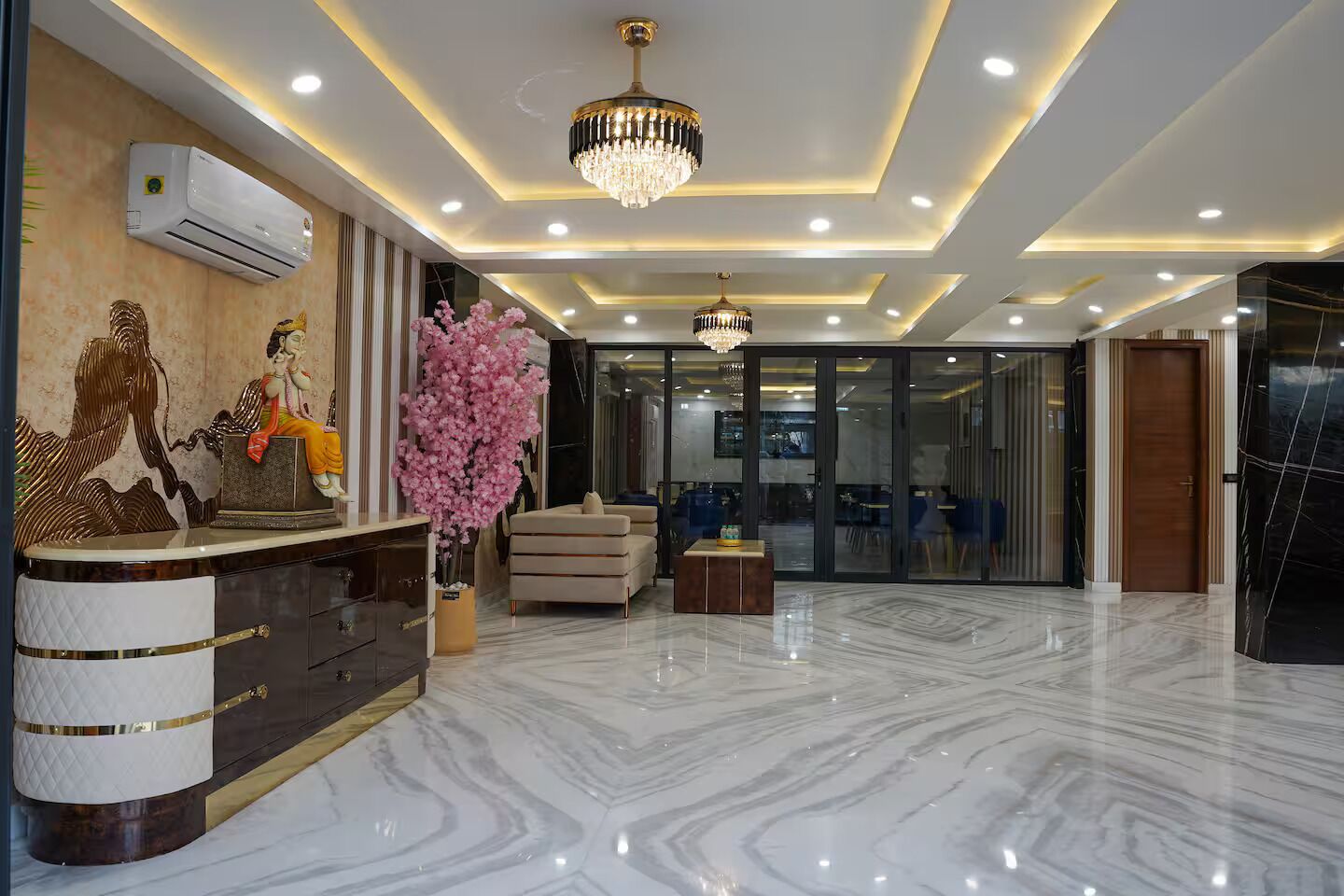 Un vestíbulo de hotel con piso de mármol, una recepción, una araña y un ventanal grande.