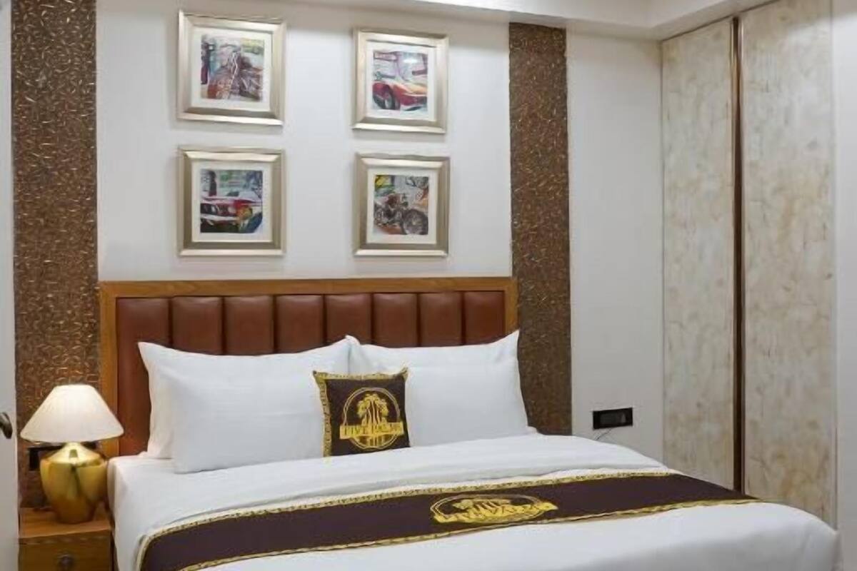 A hotel room with a large bed, a ceiling fan, recessed lighting, and framed pictures on the wall.
