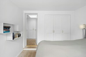 Ein Schlafzimmer mit einem Bett, einem weißen Kleiderschrank und Regalen mit Büchern.