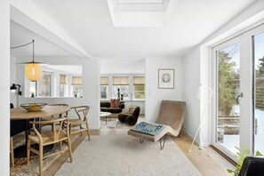 Ein modernes Interieur mit Essbereich, einer Couch, einem Sessel und einem großen Fenster.