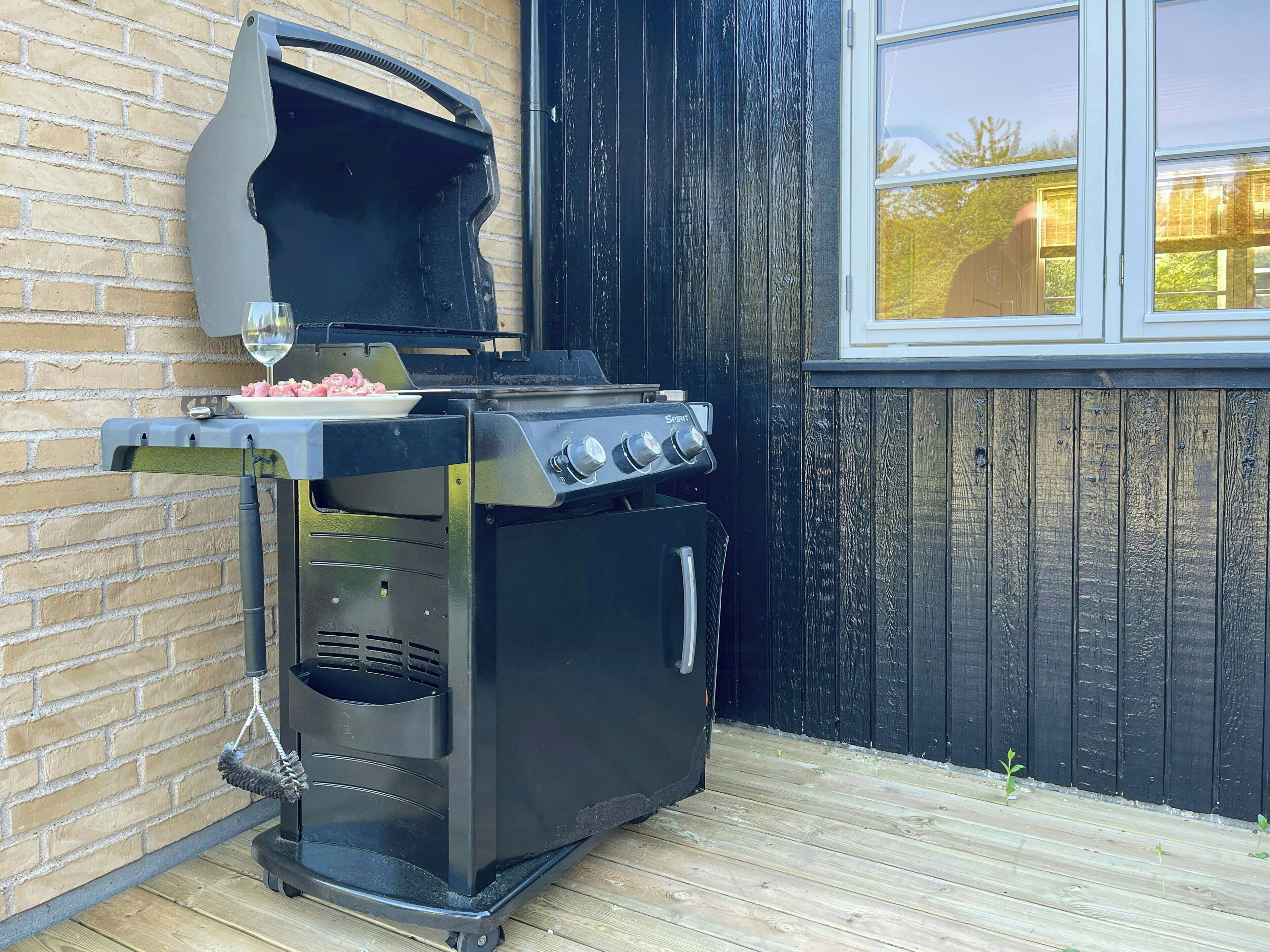 A black outdoor grill with a glass lid, a built-in oven, and a side burner.