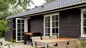 Eine Holzhütte mit einer Veranda, einem Tisch und Stühlen.