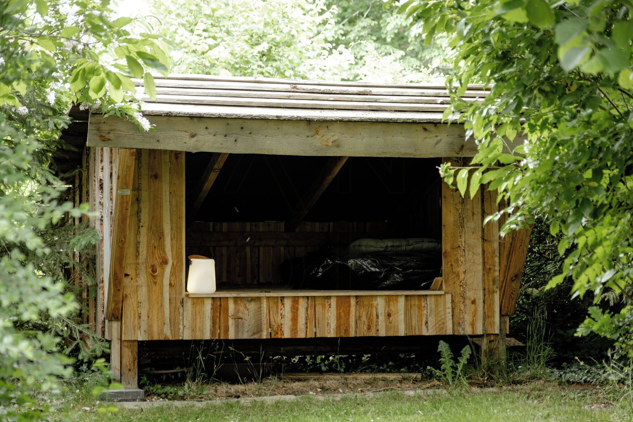 A rustic wooden structure with a slanted roof, a bench, and a small table.