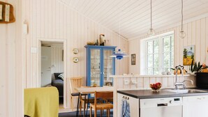 Eine Küche mit einem blauen Schrank, einem Esstisch mit Stühlen, einer Spüle und einem Fenster.