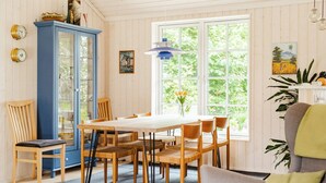 Ein Essbereich mit einem Holztisch und Stühlen, einem blauen Schrank und einem Fenster mit Blick auf Grünflächen.