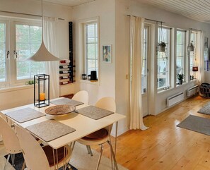 A dining area with a table, chairs, and a hanging light fixture. - House with forest and beachside location in Åhus (Åhus)