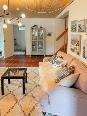 A living room with a sofa, a glass coffee table, a cabinet with glass doors, and a staircase. - House with forest and beachside location in Åhus (Åhus)