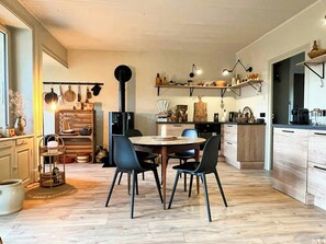 Eine moderne Küche mit Essbereich, Holzschränken und einem schwarzen Herd.