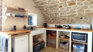 A compact kitchen with a stone ceiling, built-in shelves, a dishwasher, and a microwave. - Charming renovated workshop in Ardèche (Joyeuse)
