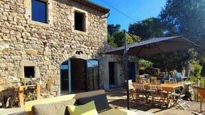 A stone building with a sofa and outdoor furniture, including a table and chairs. - Charming renovated workshop in Ardèche (Joyeuse)