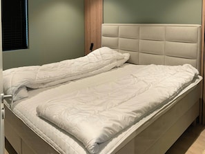 Un letto rifatto con una testiera imbottita e un comodino.