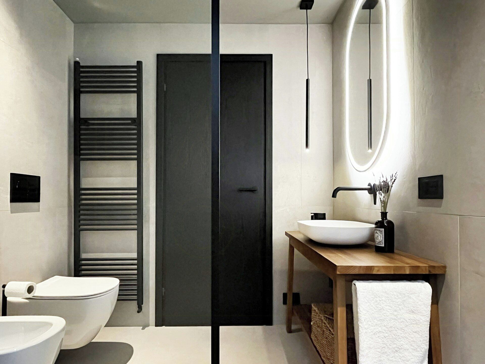 Une salle de bain moderne avec des toilettes sur pied, un lavabo encastré, un meuble-lavabo en bois, un porte-serviettes et un miroir.