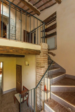 Ein mehrgeschossiges Interieur mit Treppe, Holzbalken und einer Ziegel-Säule.