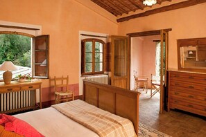 Ein Schlafzimmer mit Bett, einem Holzschrank und einem Fenster mit Blick auf Grünflächen.