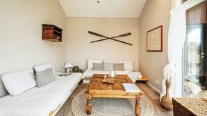 A living room with a sofa, a coffee table, a wall-mounted light fixture, and a large window. - Family house with sauna near Ålbæk (Ålbæk)