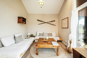 Ein Wohnzimmer mit einer Couch, einem Couchtisch, einer Wandleuchte und einem großen Fenster.