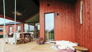 A wooden deck with a table and chairs, a hammock, and a log table. - Family house with sauna near Ålbæk (Ålbæk)