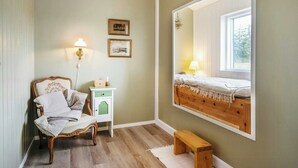 A room with a bed, a chair, a bedside table, a lamp, and a mirror reflecting the bed. - Family house with sauna near Ålbæk (Ålbæk)