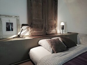 Ein Schlafzimmer mit einem Bett, zwei Nachttischlampen, einem Holzschrank und einem gerahmten Bild an der Wand.
