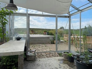 A greenhouse with a glass roof, a concrete bench, and potted plants.