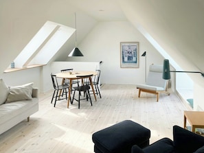 A modern loft with a dining area, a sofa, and a staircase.